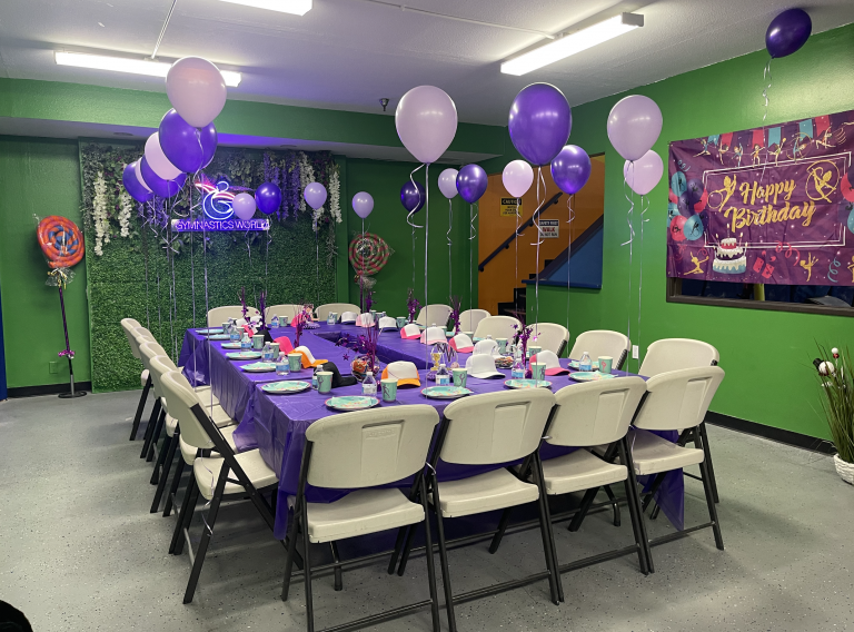 Birthday party room setup. Ballons and table cloths in purple color with a green room