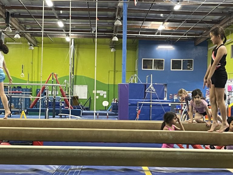 Gymnastics Facility with gymnastics equipment Colorful Mats - Girls on Balance beam